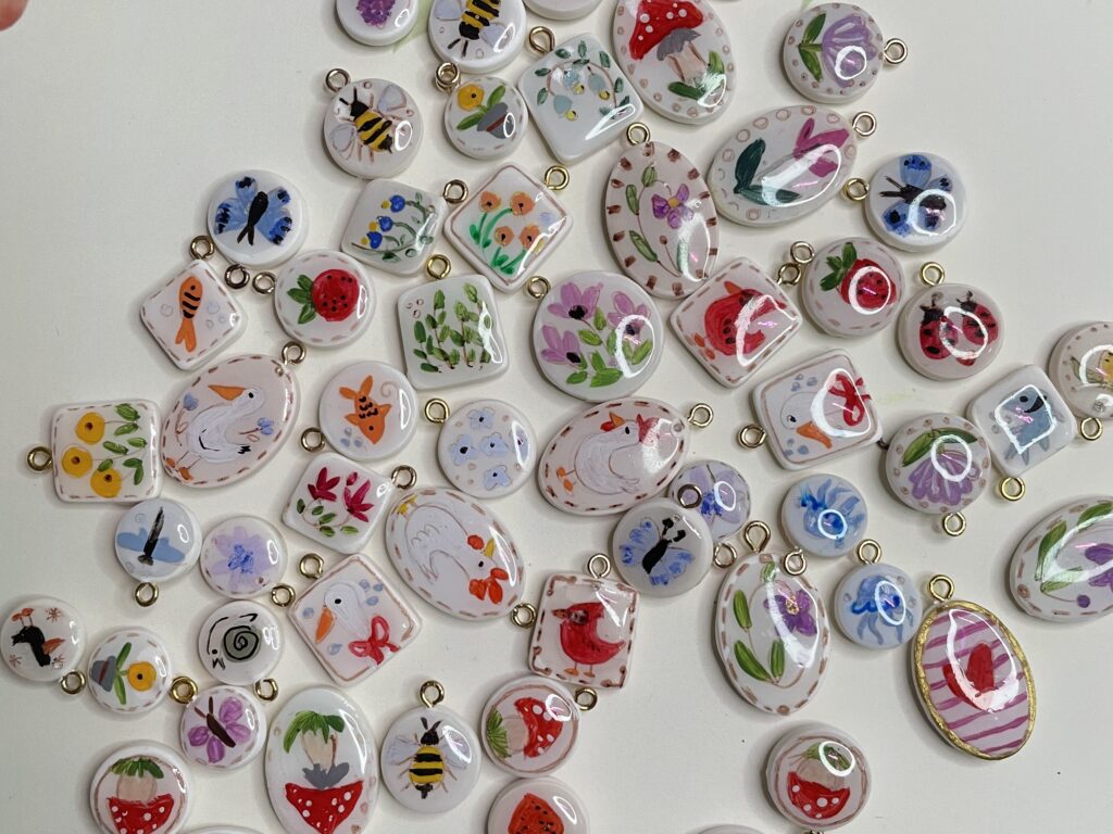 Serie di ciondoli dipinti a mano con soggetti del mondo della natura: pesci, fiori, api, farfalle, coccinelle, ricci, galline, oche, uccellini, funghi, fragole, limoni, more. 